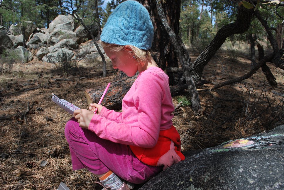 child sitting outside drawing in journal